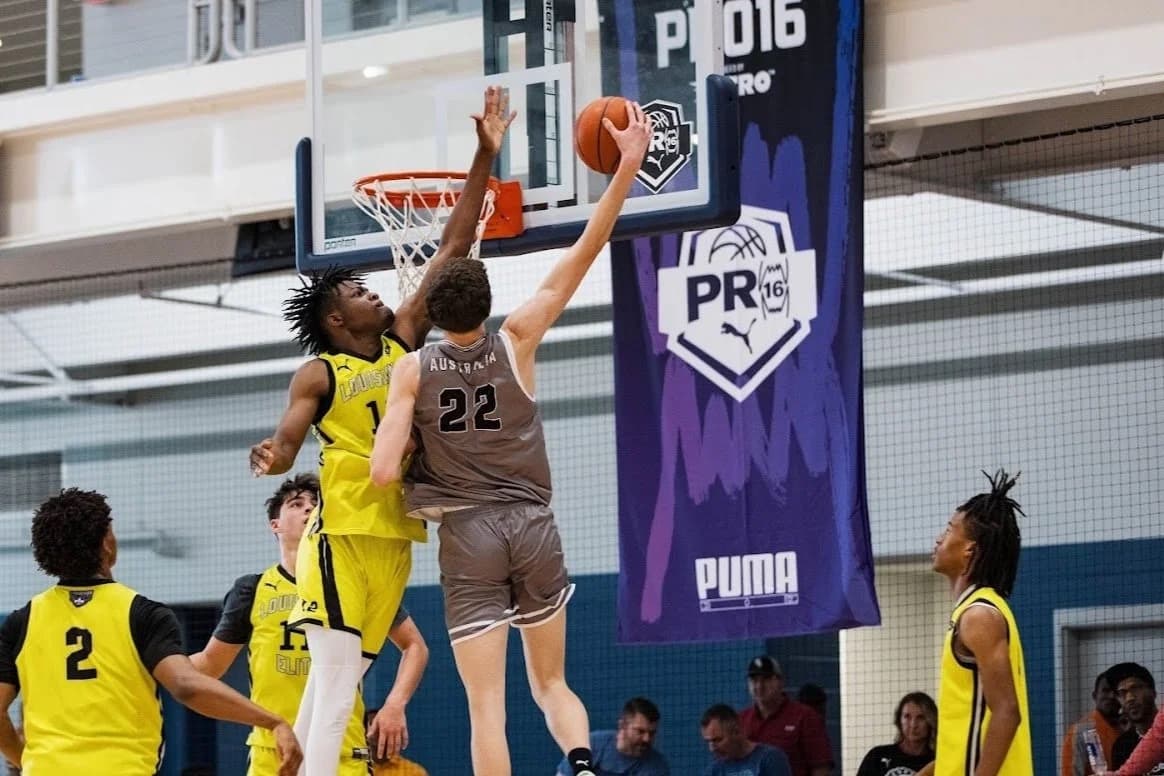 An AUSA Hoops player finishing at the rim under a PUMA PRO16 banner