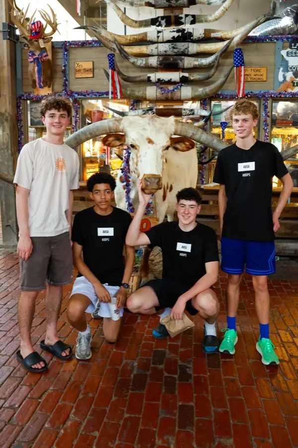 Four AUSA Hoops players posing with a longhorn steer at a Texas store